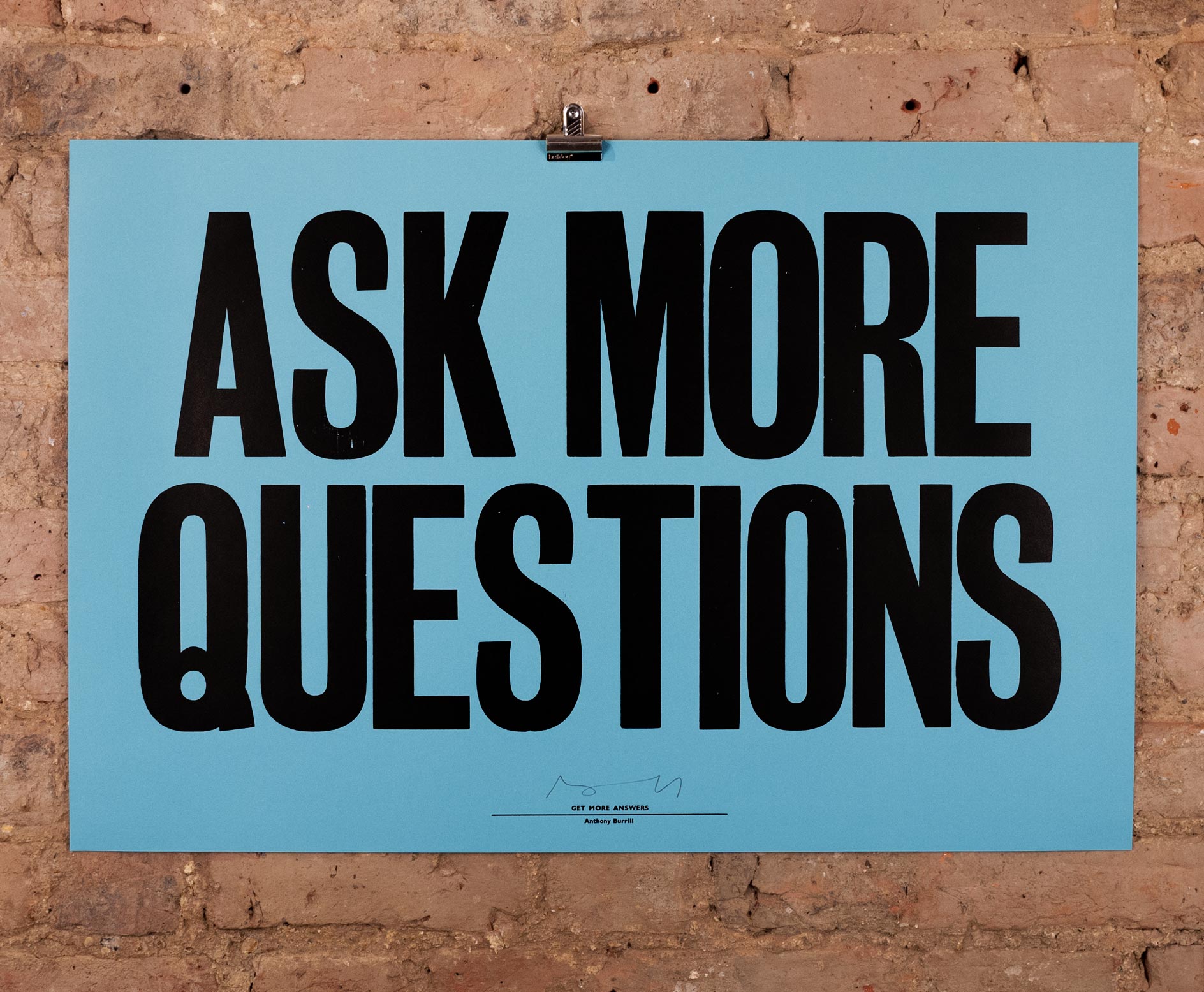 a blue sign saying Ask-More-Questions 