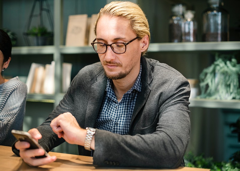 man looking at watch and phone