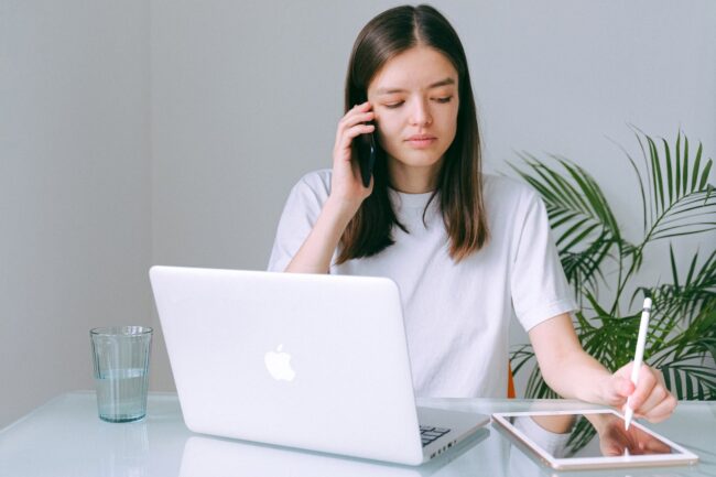 a saleswoman applying some calling tecniques in her sales routine with a laptop and an Ipad in front of her